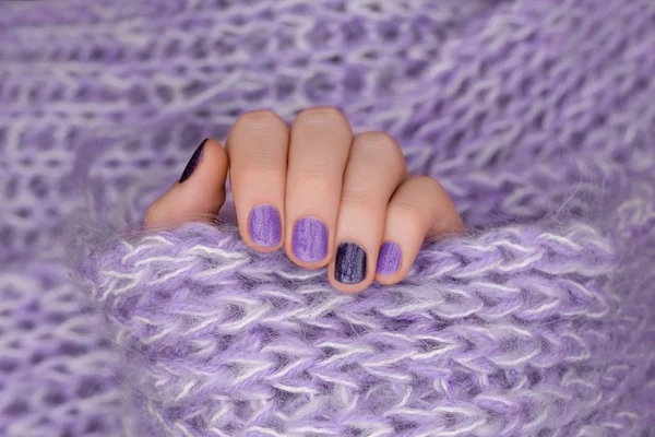 Design de unhas roxas. Mão feminina cuidada no fundo roxo . — Fotografia de Stock