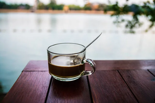 Coffee glass on wooden table with river background