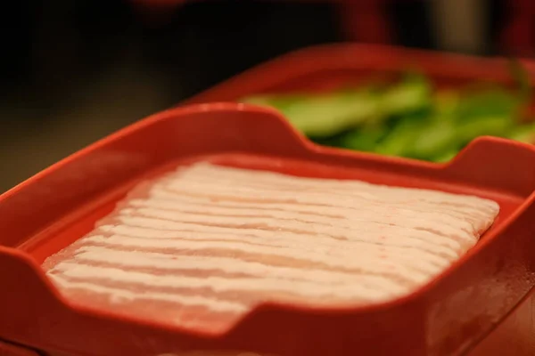 Carne di maiale cruda tagliata a fette isolata su fondo piatto rosso. Vista dall'alto . — Foto Stock