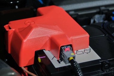 Kırmızı artı sembollü pozitif pil hücresinin plastik kapağı, batarya motor bölmesine yerleştiriliyor..