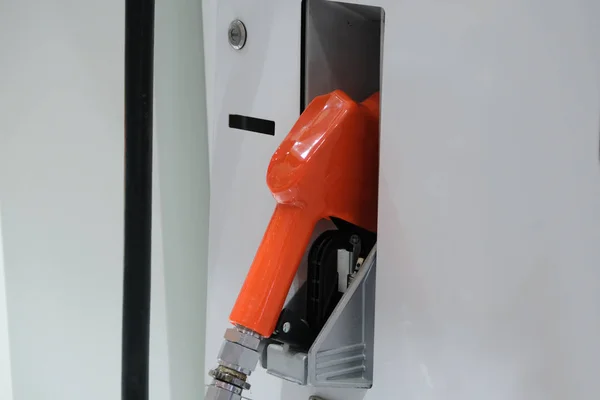 Bomba de combustível. Detalhe de uma mão laranja segurando uma bomba de combustível em uma estação — Fotografia de Stock