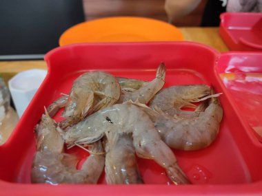 Kırmızı tabakta taze karides var.