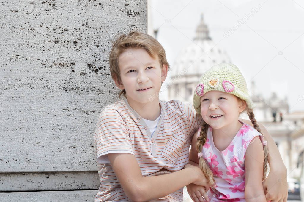 Portrait of two hugging siblings on hot summer day at city center background