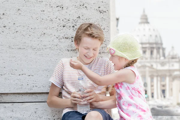 Two siblings soaking each other drinking water from plastic bottle in hot summer day — Stock Photo, Image