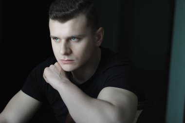 Omuz düşük anahtar aydınlatma kapalı portre üzerinde el ile genç adam