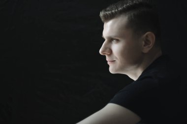 Yan görünümü baş ve omuzlar genç adam portre düşük anahtar aydınlatma