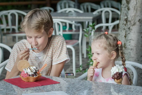 Two siblings eating dessert in Italian ice cream bar gelateria — Stock Photo, Image