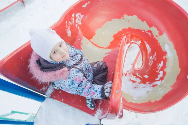 La actividad invernal de la niña en espiral de plástico tobogán de patio —  Fotos de Stock