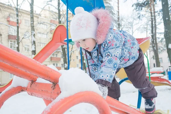 Mała dziewczynka, wspinaczka na snowy plac zabaw huśtawka — Zdjęcie stockowe