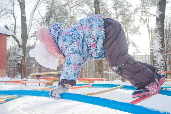 Dziewczyna, wspinaczka na zimowe monkey bar na snowy plac zabaw — Zdjęcie stockowe