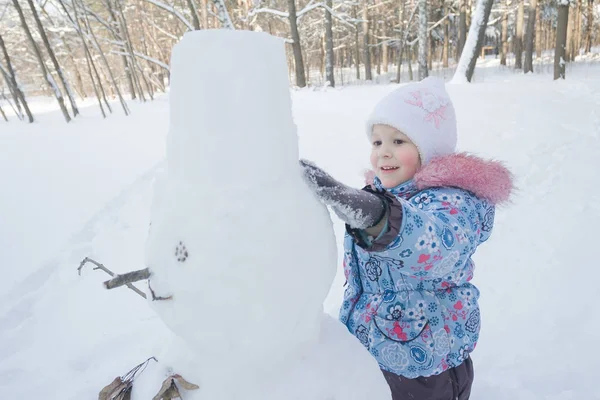 Niña alegre haciendo muñeco de nieve de tres bolas de nieve —  Fotos de Stock