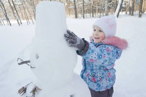 Niña feliz haciendo muñeco de nieve de invierno de nieve —  Fotos de Stock