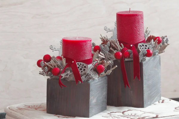 Due decorazioni floreali natalizie con candele rosse — Foto Stock