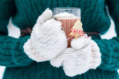 Noel sıcak kakao marshmallows ile cam bardağa tutan kadın eldivenler, yakın çekim