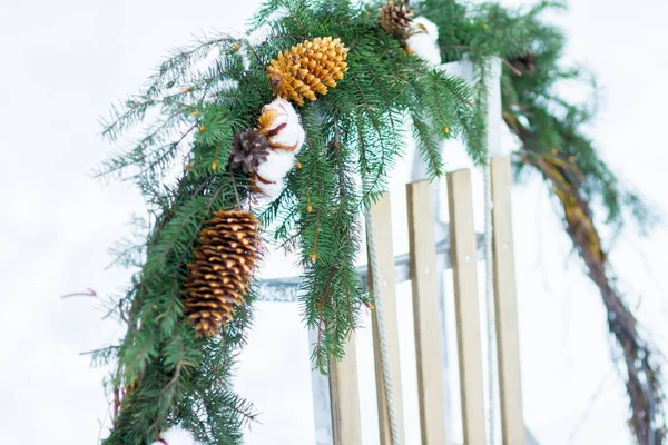 Рождественская ель и хлопчатобумажный цветок венок висит на деревянных санях на открытом воздухе — стоковое фото