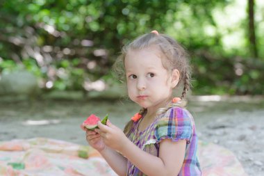 Sarışın küçük kız plaj pikniğe sulu karpuz dilimi ısırmak