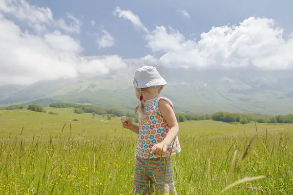 Rückansicht des blonden kleinen Mädchens in den italienischen Apenninen der Abruzzen mit Blick auf die Berge — Stockfoto