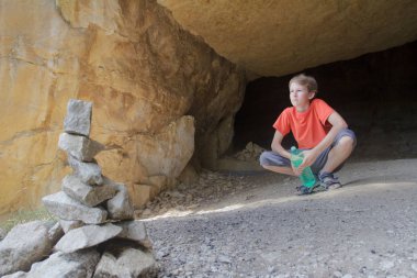 Genç çocuk ön plan, taş cairn ile dağ görünümünden rock Mağarası bakarak