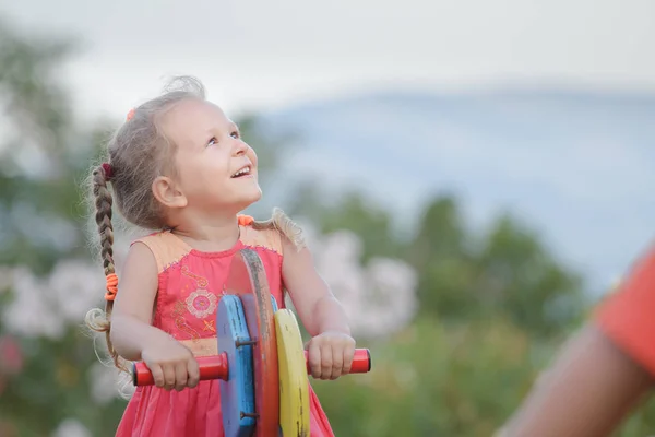 Развлекательная деятельность маленькой девочки, качающейся на деревянной игровой площадке — стоковое фото