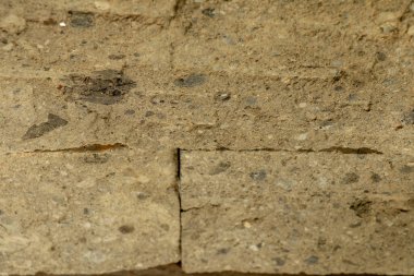 Kabaca işlenmiş taştan yapılmış taş duvar doğal renkte. Ölçekle