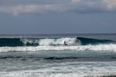 Dalgadaki genç adam. Sörfçü boruyu bırakır. Bali 'de dalgalar