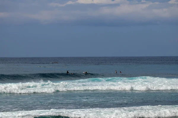 Jóvenes surfistas sentados en tablas de surf esperando la ola correcta . — Foto de Stock