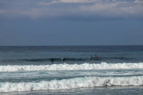 Jóvenes surfistas sentados en tablas de surf esperando la ola correcta . — Foto de Stock