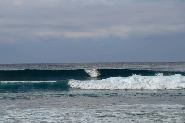 Jongeman glijdt van een golf af op een gele surfplank. Surfer op een — Stockfoto