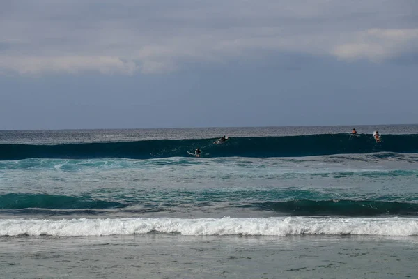 Hombre no identificado en tabla de surf esperando ola en agua azul ba — Foto de Stock