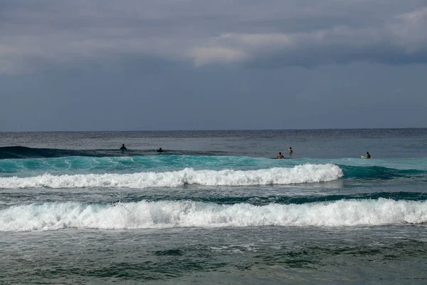 Hombre no identificado en tabla de surf esperando ola en agua azul ba — Foto de Stock