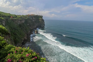 Panorama Okyanus Kıyısı 'na bak, Cliff. Çiçek ve yeşil başlıklı dikey uçurum Hint Okyanusu 'nun üzerinde bunaltıcı bir manzara. Bali adasının güneyinde, Pura Luhur Uluwatu Tapınağı. Endonezya.