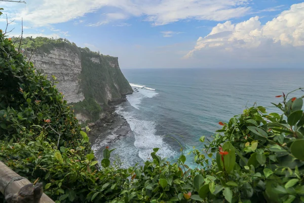 インドネシアのバリ島にあるパビリオンと青い海を持つウルワツ崖の景色 1日の間にカラフルな花を前景にプーラLuhur Uluwatu寺の美しい景色 高い崖の風景海岸風景 — ストック写真