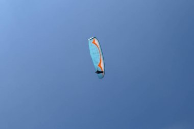 Gökyüzünde paraşütle atlıyor. Paraglider güneşli bir günde uçuyor. Turkuaz arka planda uçan güzel bir paraglider. Aktif yaşam tarzı ve ekstrem spor macerası kavramı. İzole edilmiş.