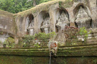 Udayan Hanedanı 'nın kraliyet mezarlarında kutsal suyla dolu Gargoyles. Gunung Kawi Tapınağı 'ndaki antik kraliyet mezarları. Taş kayalıklara oyulmuş kraliyet mezarları etrafında toplanmış cenaze kompleksi, Bali.