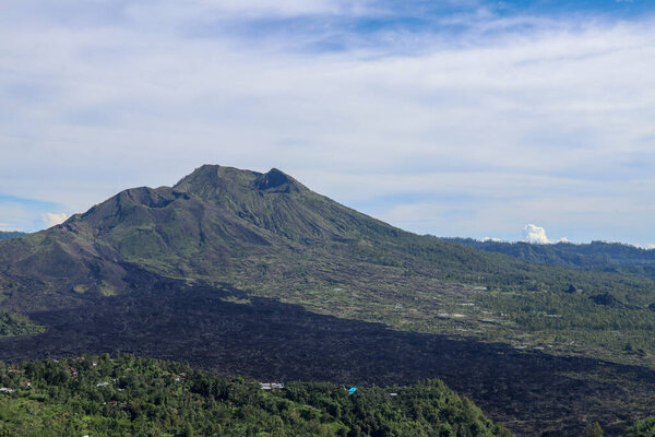 Volcano landscape with lava fields, pine tree forest and farms and houses on the slopes. Kintamani is a village on the western edge of the larger caldera wall of Gunung Batur in Bali, Indonesia.