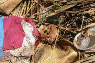 Endonezya, Bali 'de geleneksel defin yöntemleri olan, renkli giysiler giymiş, yerde yatan ölü bir adamın cesedine yaklaş. Bali 'deki Kuburan Terunyan Mezarlığı. Cesetler toprağın üstünde gömülü..
