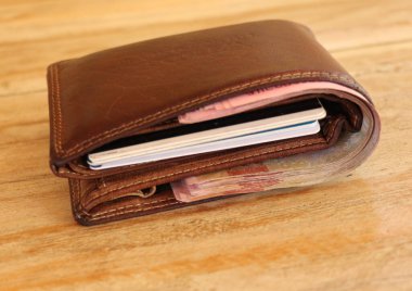 Banknotlar ve kredi kartlarıyla dolu kahverengi deri cüzdan. Ahşap bir masada erkek cüzdanı. Kapalı kahverengi bir çantada para. Projeniz için en iyi arkaplan.