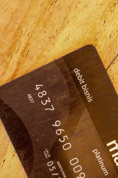 Close-up of credit or debit payment card without chip. Black business credit card on wooden background. Best for your project.