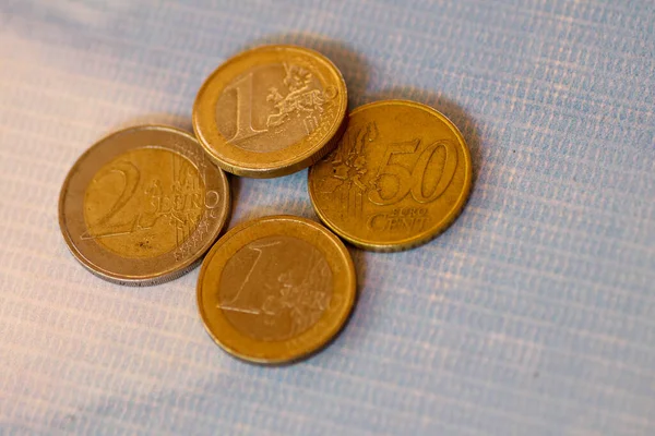 Euro coins stacked on each other in different positions. A closeup of coins a blue table under the lights. Collection of euro coin lies on the table. Coin texture. Business and finance concept.