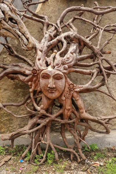 Sun with face made of tree root. Wooden decoration. Dried fibrou