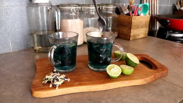 Une femme presse un citron dans un verre de thé thaï bleu floral Blue Butterfly Pea tea. Réaction du thé bleu au jus de citron. Le thé bleu devient violet — Video