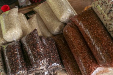 Plastik süpürge torbasında beş farklı pirinç türü. Kahverengi arka planda küçük plastik torbalarda çeşitli Groats 'lar. Pirinç ve yulaf ezmesi, karabuğday ve darı.