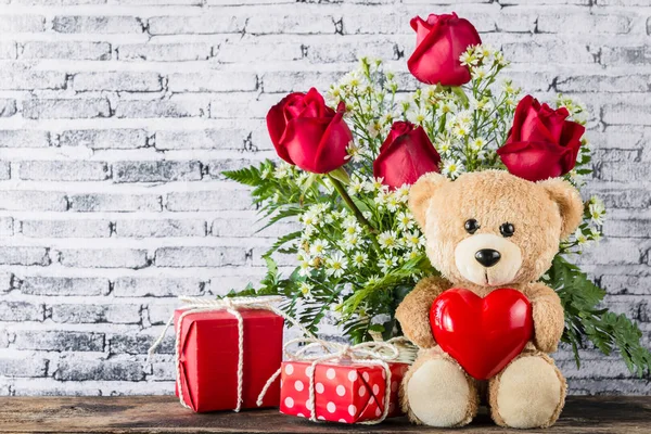 Плюшевий ведмідь тримає повітряну кулю у формі серця з червоною подарунковою коробкою — стокове фото