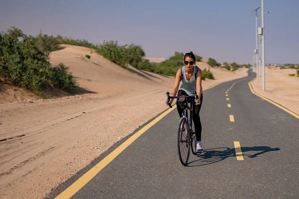 Lady rides cycle on the desert track in UAE