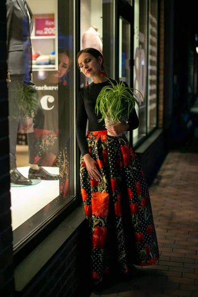 Retrato de uma jovem mulher de pé perto de uma vitrine — Fotografia de Stock