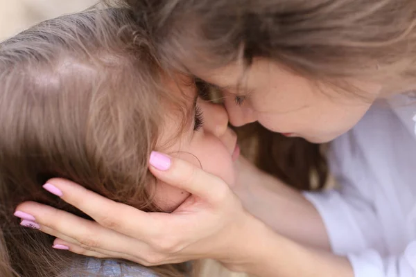 mom touches the face of her little daughter