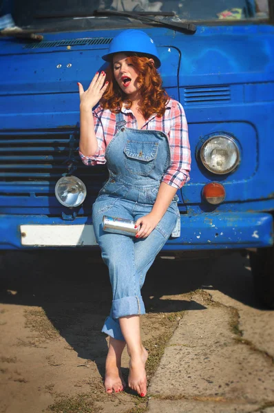 Vertical photo of a girl in denim overalls sitting on a bumper o — Stok fotoğraf