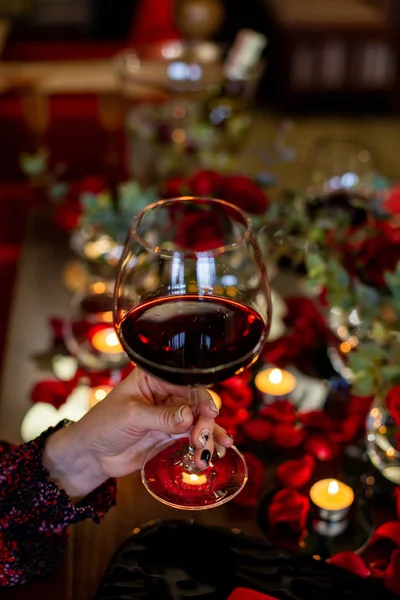Pionowe zdjęcie samicy dłoni, która trzyma szklankę z czerwonym winem — Zdjęcie stockowe