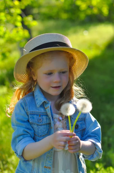 Vertikalt soligt foto av liten glad flicka med maskrosor — Stockfoto