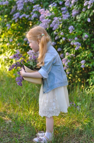 一个滑稽小女孩在紫丁香背景上的纵向照片 — 图库照片